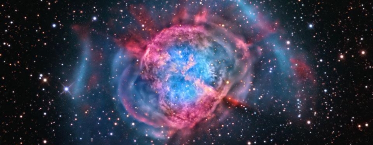 A telescope photo of a nebula in outer space in blue and pink color.