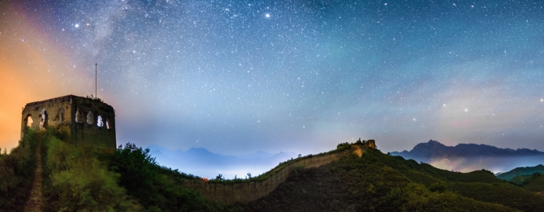 The Great Wall of China under the starry night sky with signing light.