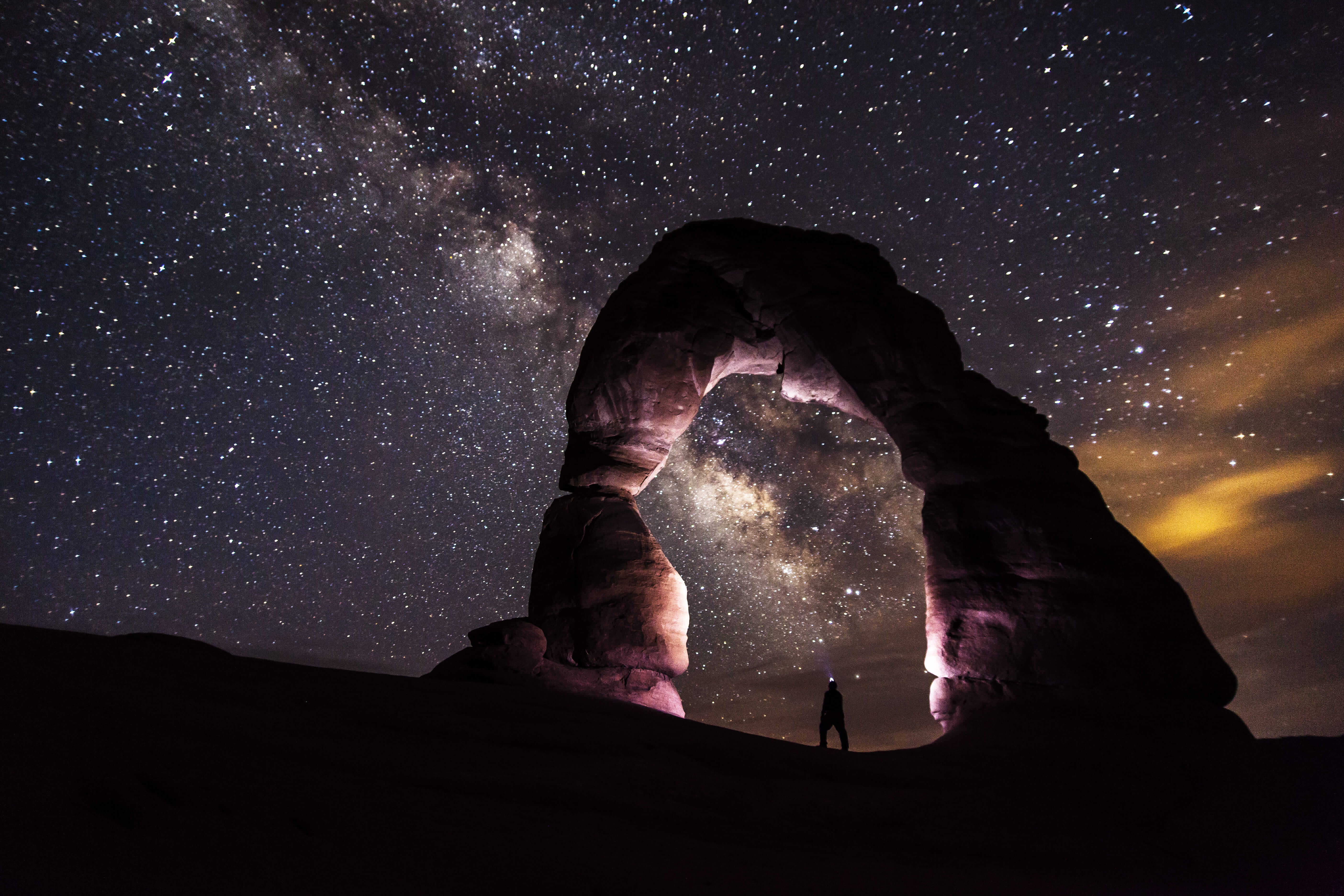 A person standing in the stone arch watching stars