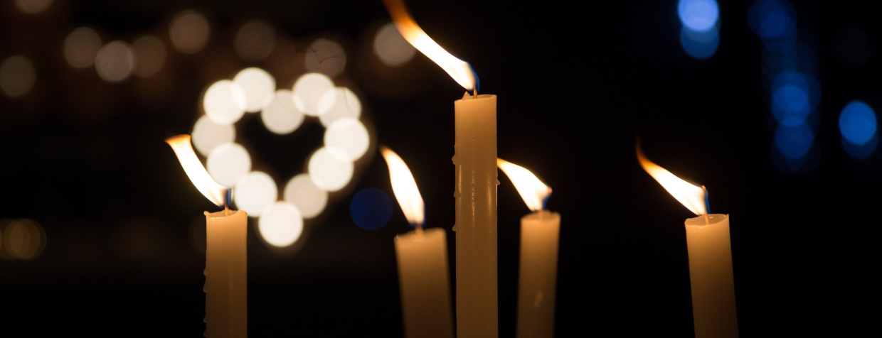 Velas acesas com uma luz em formato de coração ao fundo.