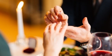 Un uomo che mette un anello di fidanzamento al dito di una donna.