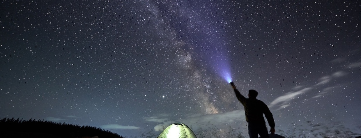 Un homme observant les étoiles sous un ciel étoilé.