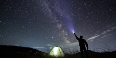 Un hombre observando las estrellas bajo un cielo estrellado.