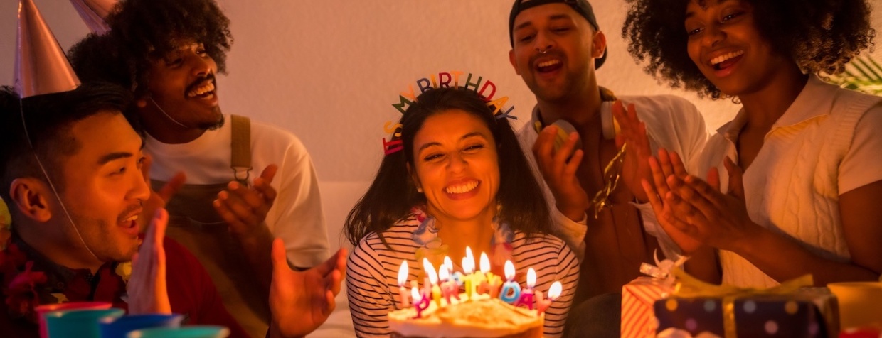 Eine Gruppe von Freunden feiert einen Geburtstag mit Kuchen und Kerzen.