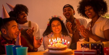 Un gruppo di amici che festeggia un compleanno con torta e candeline.
