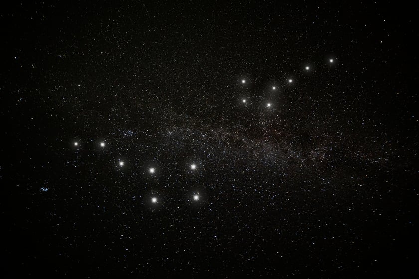 The Big Dipper and the Little Dipper side by side in the dark sky above a treeline