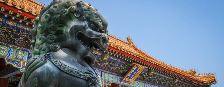 A statue of an evil dragon and a traditional Chinese house.