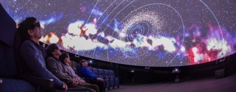 People with 3d glasses watch a movie about space in a 3D cinema theater.