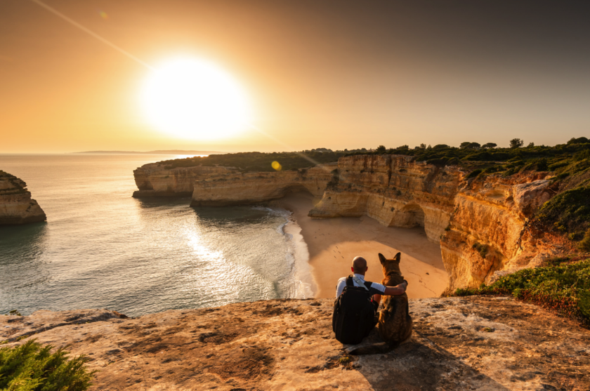 A guy sitting on a cliff with his dog