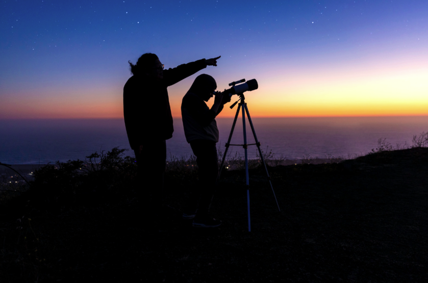 Two people looking at stars with a telescope