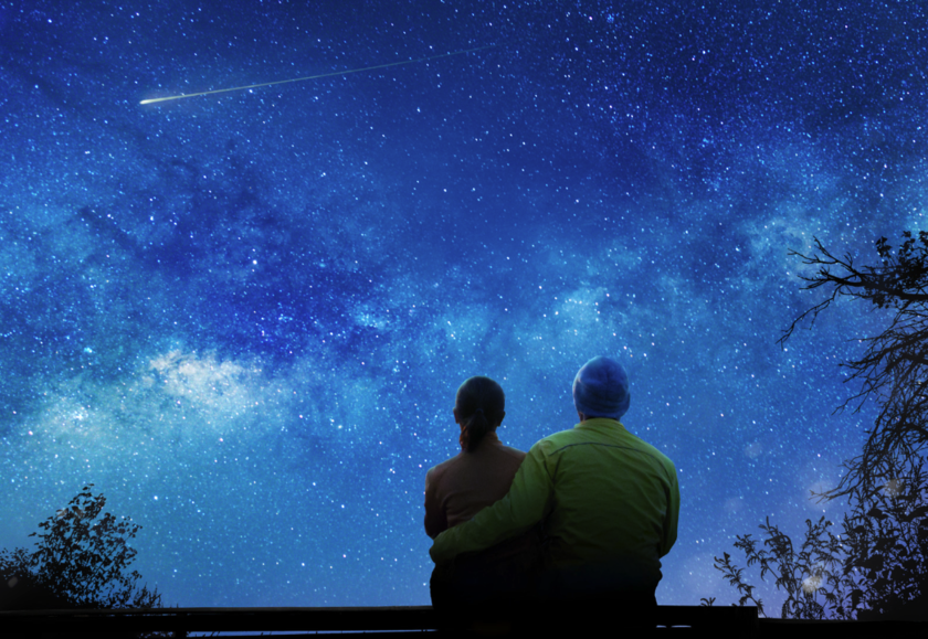 Two people watching the night sky and stars falling