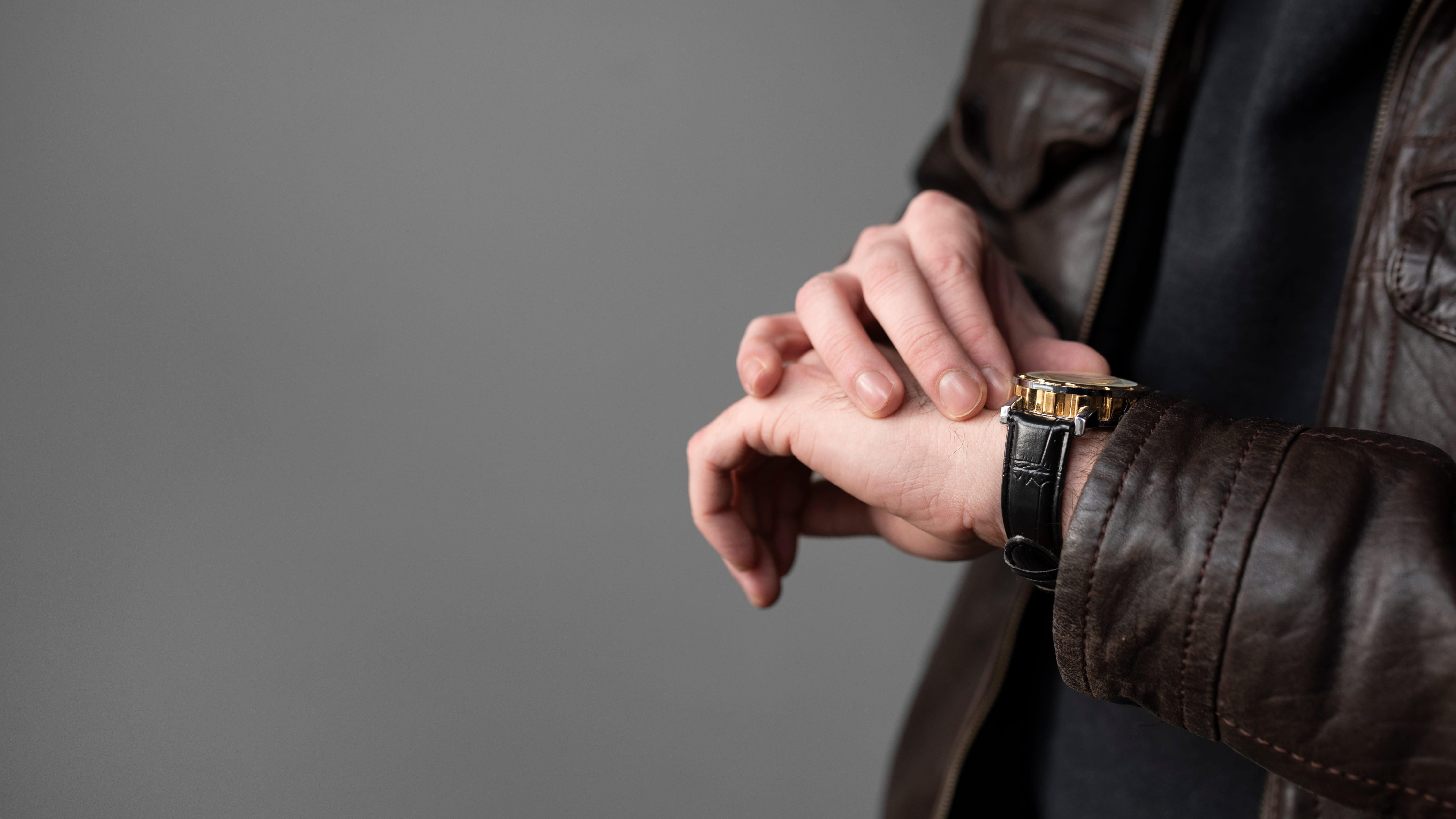 Um homem usando um relógio com pulseira de couro preta.