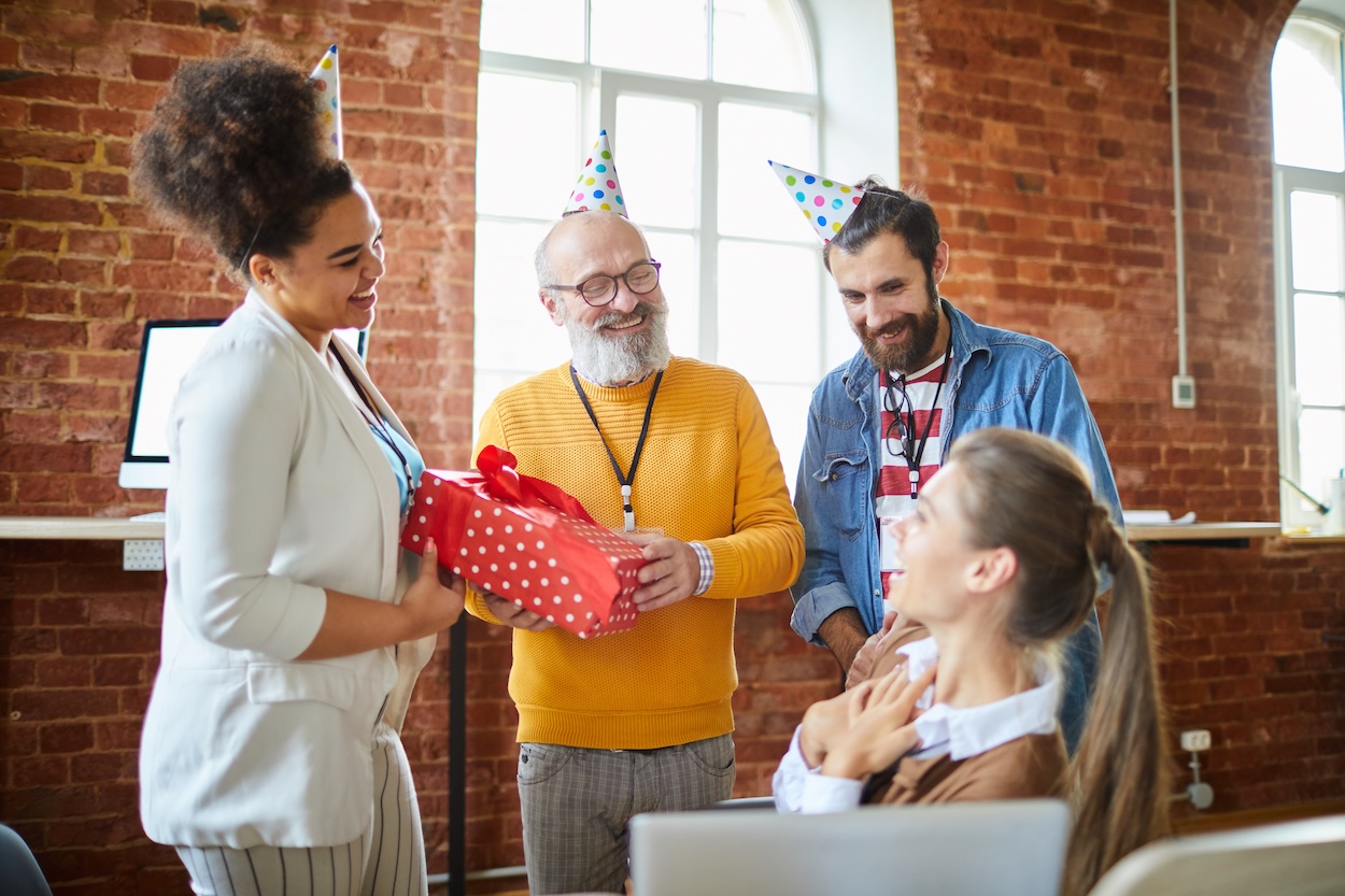 Eine Gruppe von drei Personen gratuliert ihrer Kollegin zum Geburtstag.