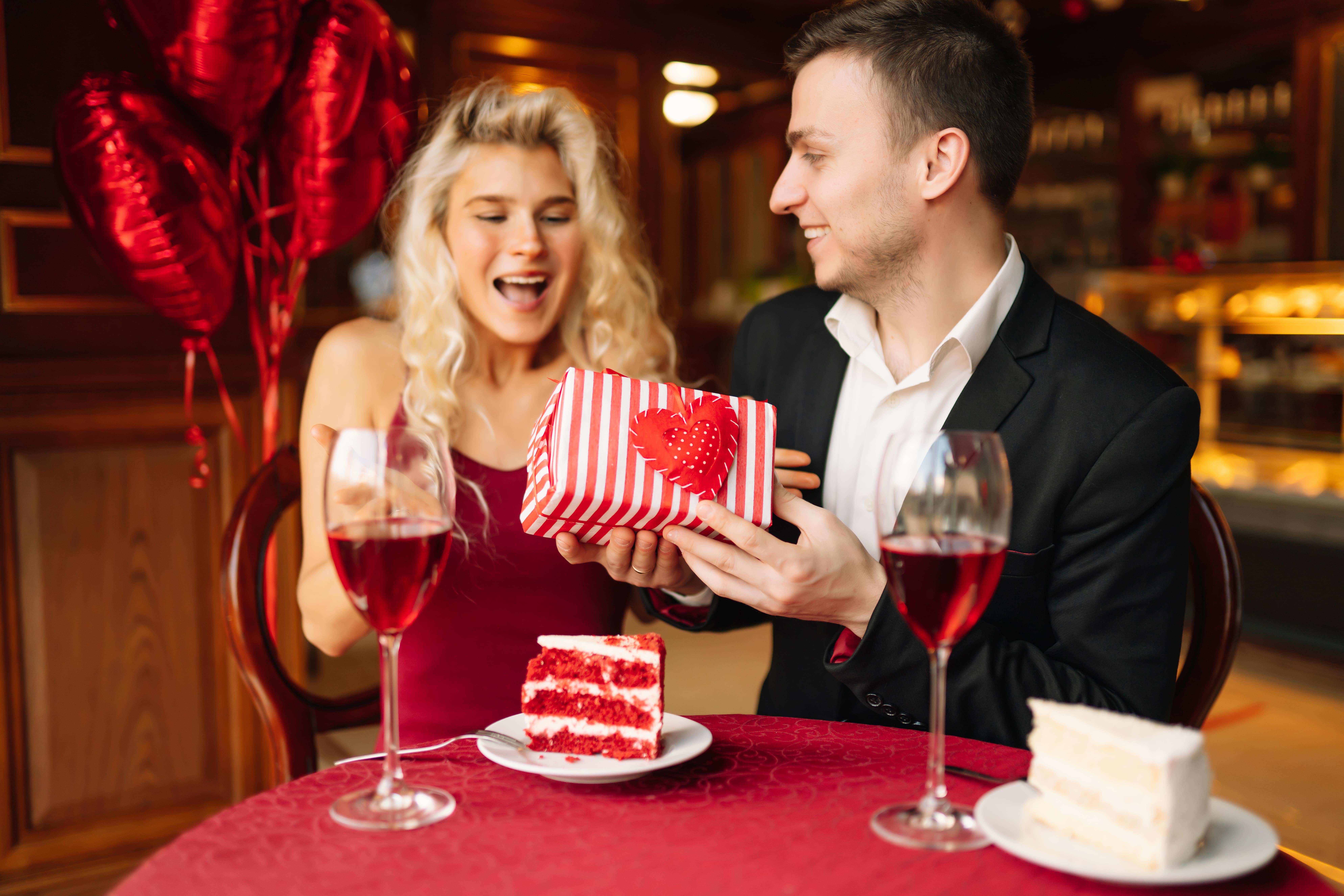A happy couple exchanging gifts over wine and cake.