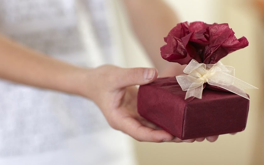 A person holding a red gift box with a beige bow