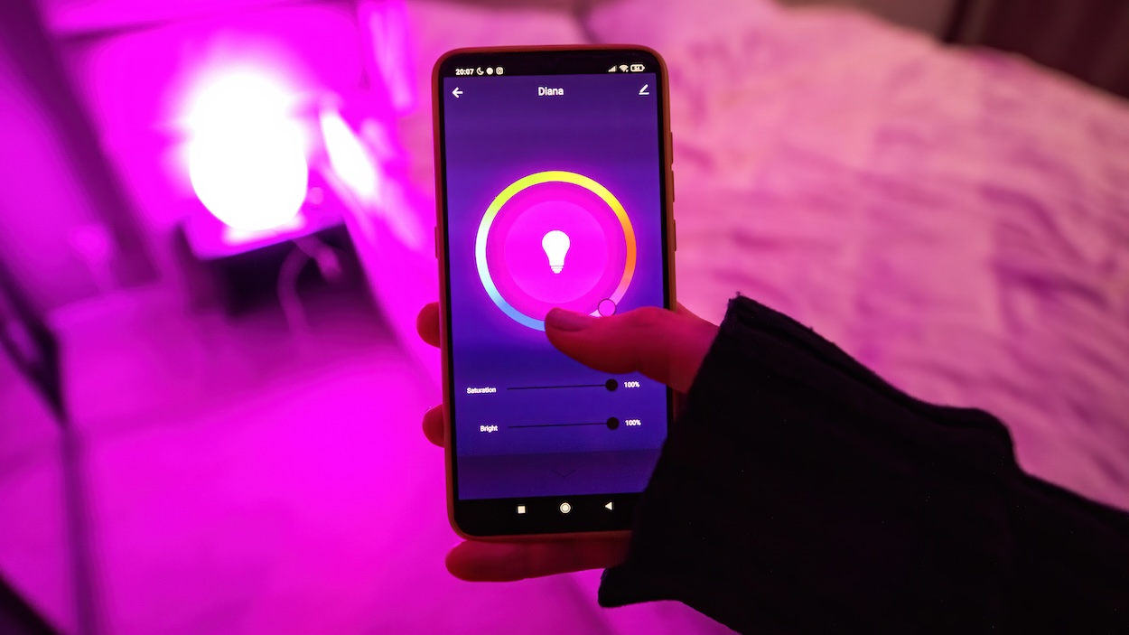 Eine Hand stellt die intelligente Beleuchtung &uuml;ber ein Smartphone ein.