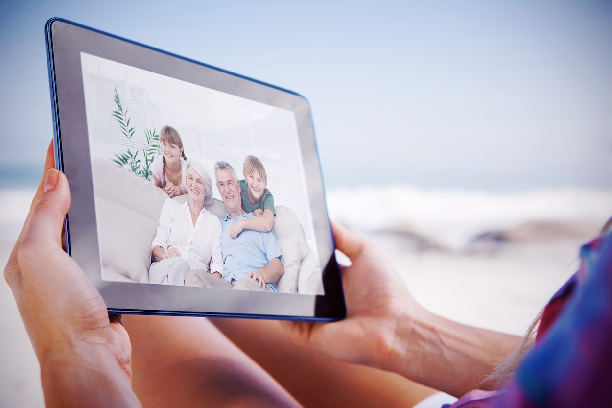 Una mujer sosteniendo un marco de fotos digital que muestra a una familia.