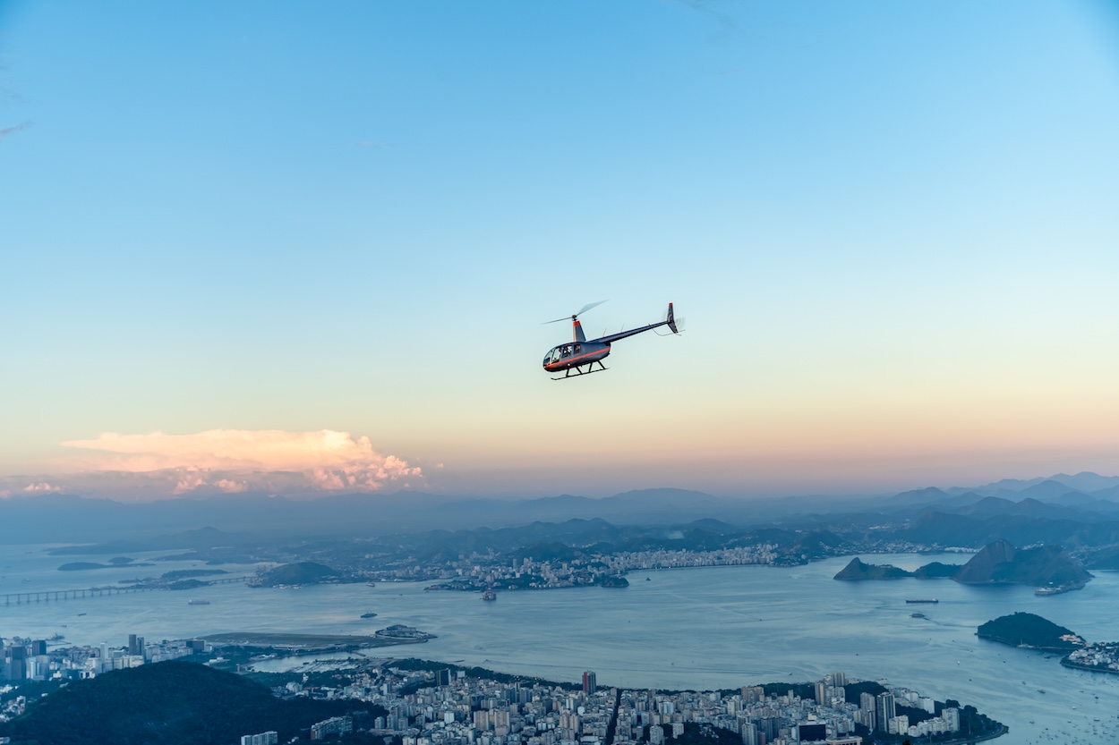 A helicopter flying over a beautiful city and mountain landscape.