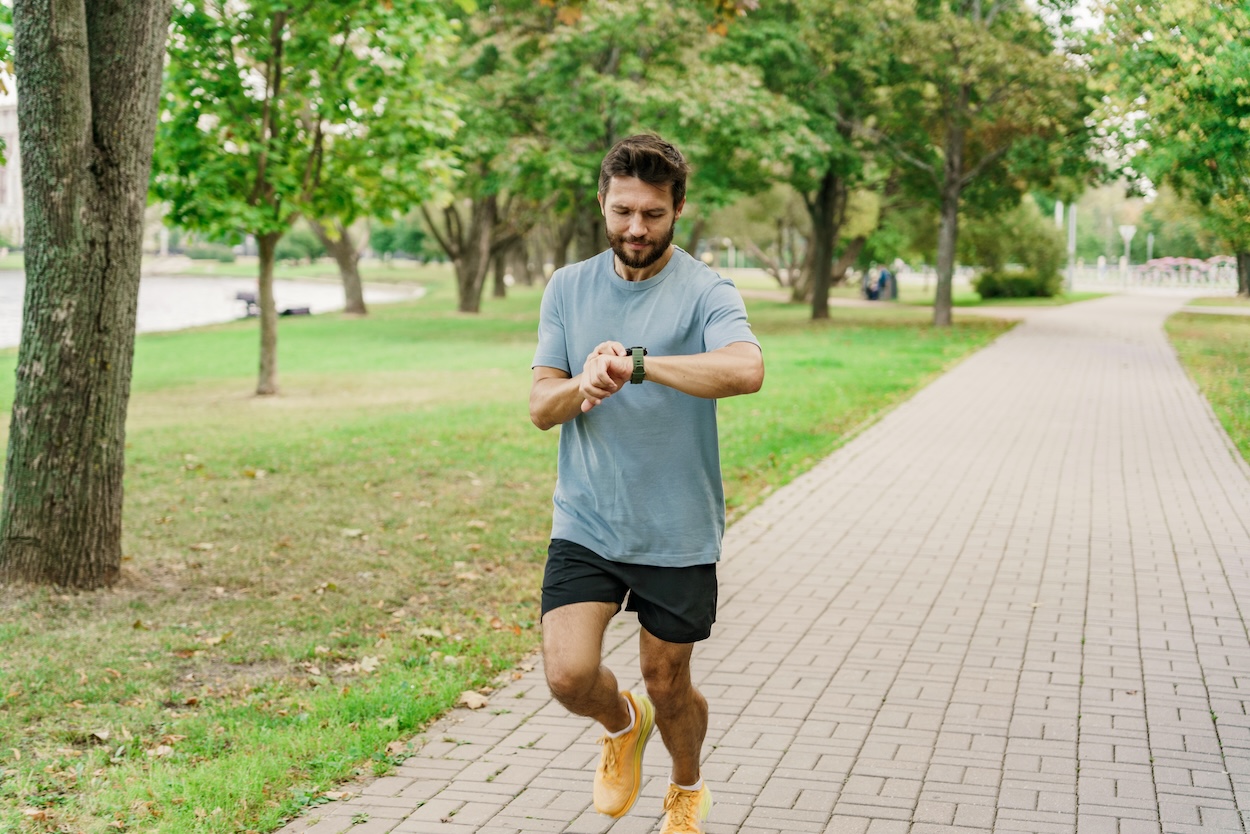 Ein Mann joggt und schaut auf seine Smartwatch.