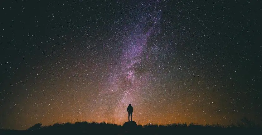 A person standing in the dark and looking up at the Milky Way