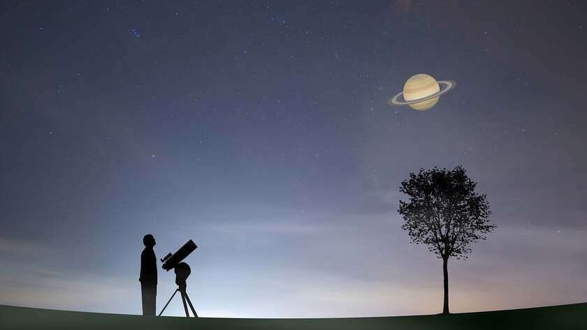 A person standing with a telescope and watching the sky in which the Saturn is visible