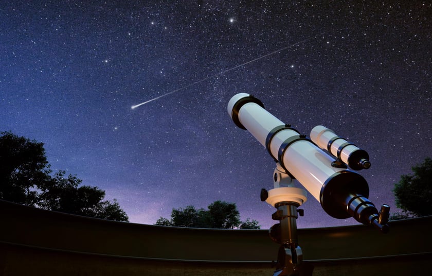 A telescope pointed at the night sky with shooting stars