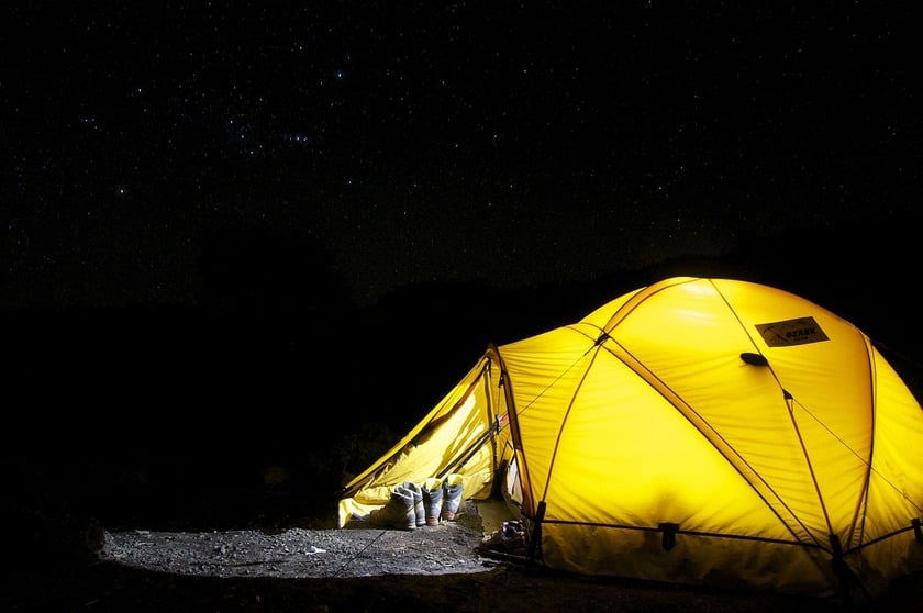 A yellow tent made to watch the dark sky full of stars above it