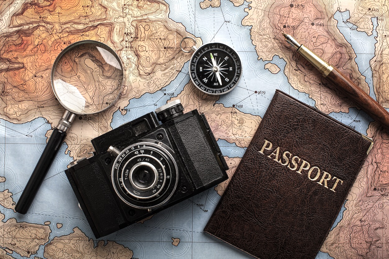 A vintage camera and a leather bound passport set on a map.