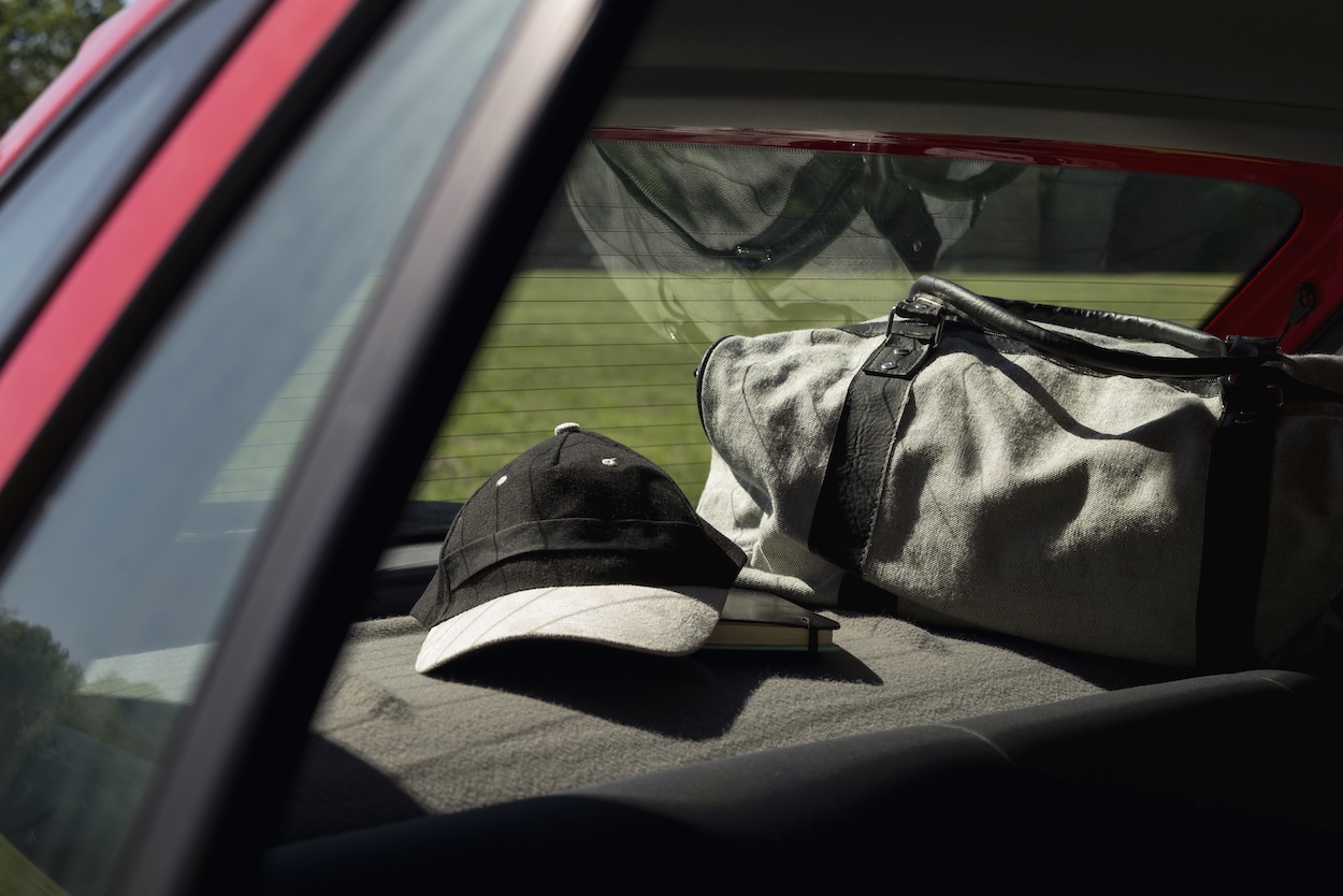 A duffel bag and a cap packed in a car.